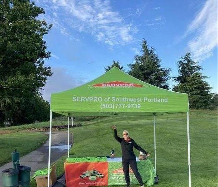Sponsorship, with woman standing under green SERVPRO tent
